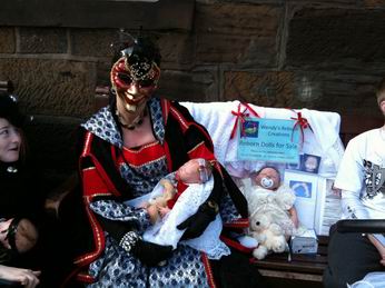 Photo of a gothic woman holding a baby doll