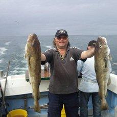 Photo of fisherman and two cod