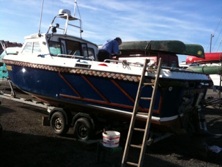 Photo of a boat owner painting his boat on the Marina